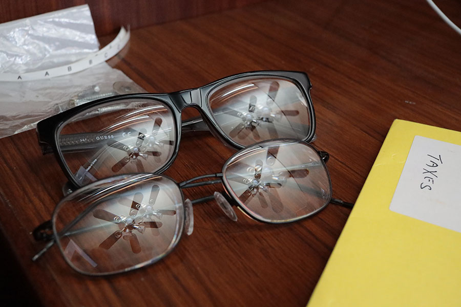 Two Pairs of Glasses on Desk With Reflected Ceiling Fans